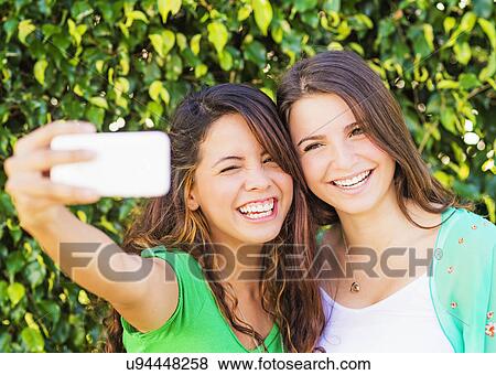 Portrait of female friends (14-15) making selfie View Large Photo Image Stock Photo - Portrait of female friends (14-15) making selfie. Fotosearch