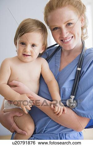 Portrait of female nurse carrying baby boy (12-17 months) View Large Photo Image Stock Photograph - Portrait of female nurse carrying baby boy (12-17 months). Fotosearch