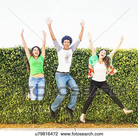 Stock Image - Portrait of friends (14-15) jumping. Fotosearch