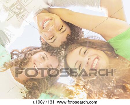 Stock Image - Portrait of friends (14-15) looking down. Fotosearch