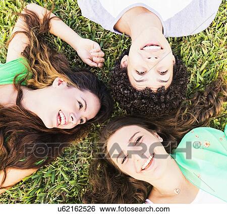 Stock Photograph - Portrait of friends (14-15) lying on grass. Fotosearch