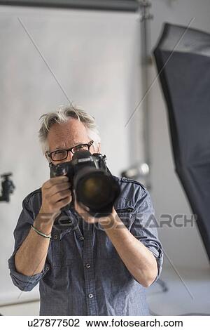 Stock Image - Portrait of photographer in his studio taking shot. Fotosearch