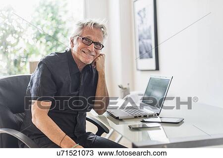 Portrait of smiling senior man sitting in home office View Large Photo Image Stock Image - Portrait of smiling senior man sitting in home office. Fotosearch