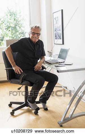 Portrait of smiling senior man sitting in home office View Large Photo Image Stock Photo - Portrait of smiling senior man sitting in home office. Fotosearch