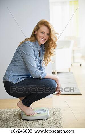 Portrait of woman crouching on weight scale View Large Photo Image Stock Photo - Portrait of woman crouching on weight scale. Fotosearch