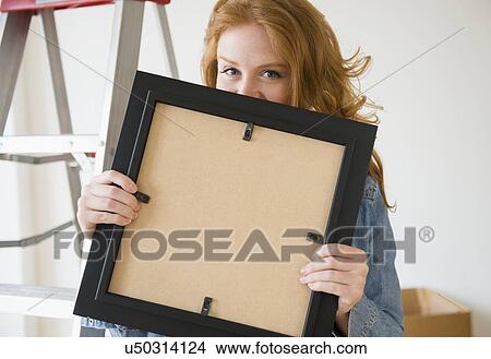 Portrait of woman holding picture frame View Large Photo Image Picture - Portrait of woman holding picture frame . Fotosearch