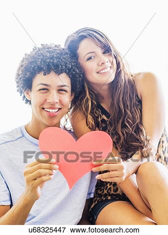 Stock Photo - Portrait of young couple with paper heart. Fotosearch