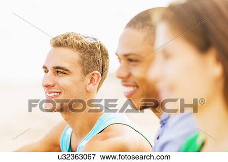 Portrait of young man with defocused view of friends in foreground View Large Photo Image Stock Photo - Portrait of young man with defocused view of friends in foreground. Fotosearch