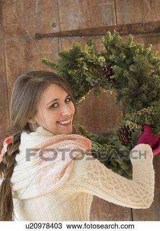 Portrait of young woman hanging christmas wreath on door View Large Photo Image Stock Image - Portrait of young woman hanging christmas wreath on door. Fotosearch