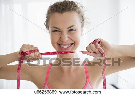Stock Photo - Portrait of young woman holding measurement tape. Fotosearch