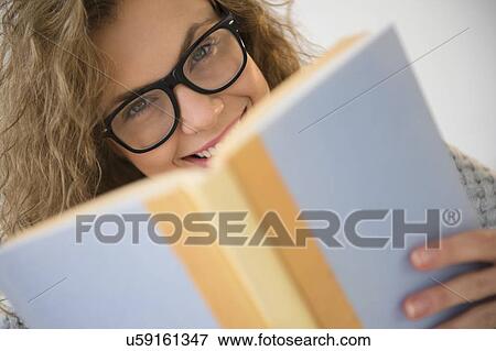 Stock Photo - Portrait of young woman wearing glasses, holding book. Fotosearch