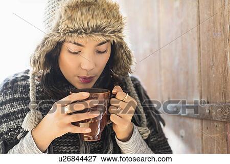 Portrait of young woman wearing warm hat, blowing on cup of drink View Large Photo Image Stock Photo - Portrait of young woman wearing warm hat, blowing on cup of drink. Fotosearch