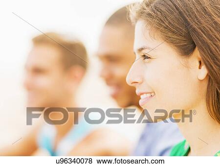 Portrait of young woman with male friends in background View Large Photo Image Stock Photo - Portrait of young woman with male friends in background. Fotosearch