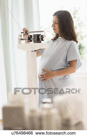 Pregnant woman in doctors office standing on scale View Large Photo Image Stock Photograph - Pregnant woman in doctors office standing on scale. Fotosearch