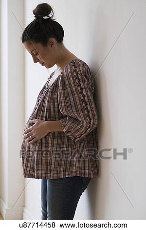 Stock Photo - Pregnant woman leaning against wall. Fotosearch