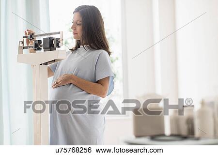 Stock Photograph - Pregnant woman on scale in doctor's office. Fotosearch