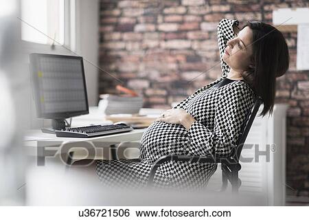 Stock Photograph - Pregnant woman relaxing in office. Fotosearch
