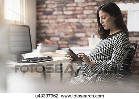 Pregnant woman working in office View Large Photo Image Stock Image - Pregnant woman working in office. Fotosearch