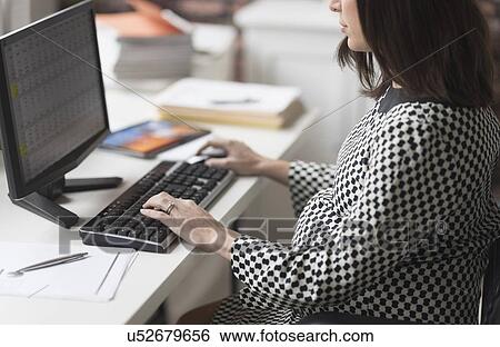 Stock Photograph - Pregnant woman working in office. Fotosearch