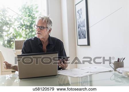 Senior man sitting in home office and using laptop View Large Photo Image Stock Photo - Senior man sitting in home office and using laptop. Fotosearch