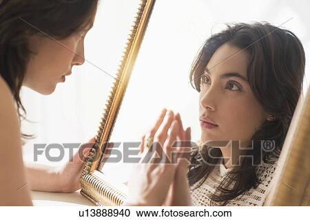Serious young woman looking into mirror View Large Photo Image Stock Image - Serious young woman looking into mirror. Fotosearch