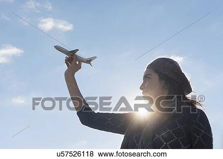 Side view of young woman holding model airplane View Large Photo Image Stock Photo - Side view of young woman holding model airplane. Fotosearch