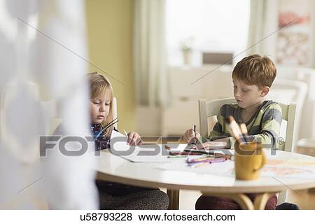 Stock Photo - Sister and brother (4-5, 6-7) drawing in family room. Fotosearch