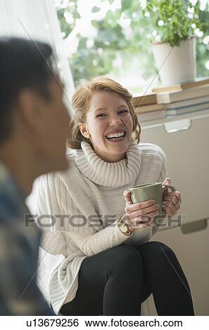 Stock Photograph - Smiling woman sitting and holding mug. Fotosearch