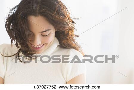 Stock Image - Smiling young woman looking down. Fotosearch