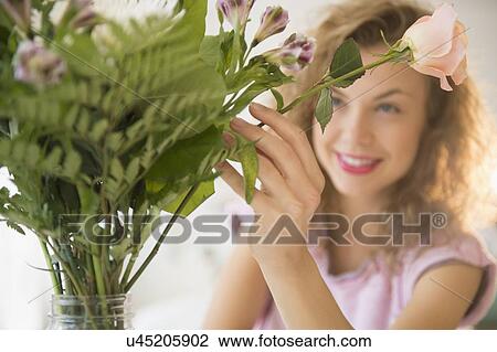 Smiling young woman putting flowers in vase View Large Photo Image Stock Image - Smiling young woman putting flowers in vase. Fotosearch