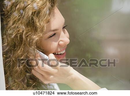Picture - Smiling young woman using mobile phone. Fotosearch