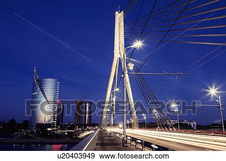 Suspension bridge with skyscrapers on background at night View Large Photo Image Stock Photo - Suspension bridge with skyscrapers on background at night. Fotosearch