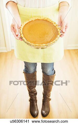 Stock Image - Woman holding pumpkin pie. Fotosearch