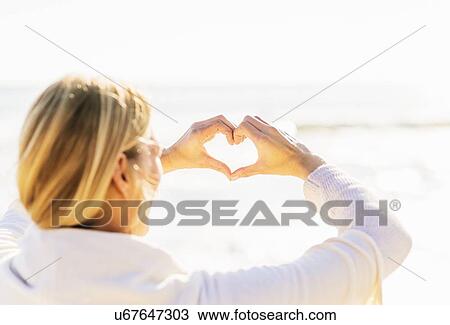 Stock Image - Woman showing heart shape with hands. Fotosearch