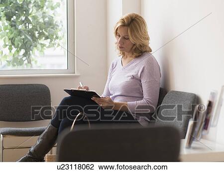 Stock Image - Woman sitting in waiting room. Fotosearch