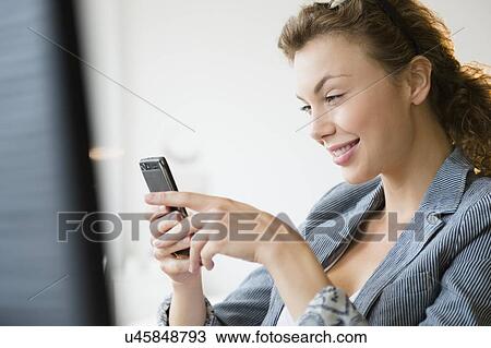 Stock Image - Young businesswoman using mobile phone. Fotosearch