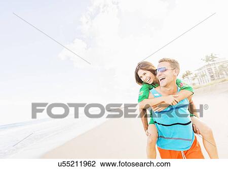 Young couple doing piggyback ride on beach View Large Photo Image Stock Image - Young couple doing piggyback ride on beach. Fotosearch