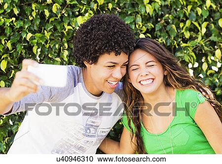 Stock Image - Young man and young woman making selfie. Fotosearch