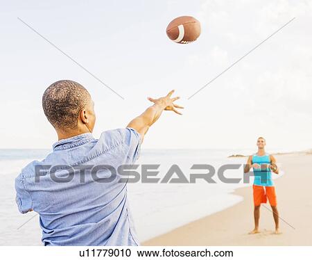 Young men playing football on beach View Large Photo Image Stock Image - Young men playing football on beach . Fotosearch