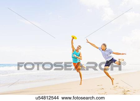 Young men playing plastic disc on beach View Large Photo Image Picture - Young men playing plastic disc on beach . Fotosearch
