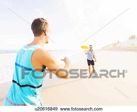 Young men playing plastic disc on beach View Large Photo Image Stock Photo - Young men playing plastic disc on beach . Fotosearch