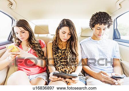 Stock Photo - Young people and teenager (14-15) using cell phones in car. Fotosearch