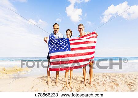 Young people holding American flag on beach View Large Photo Image Stock Image - Young people holding American flag on beach. Fotosearch