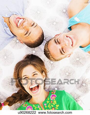 Stock Image - Young people lying down and laughing. Fotosearch