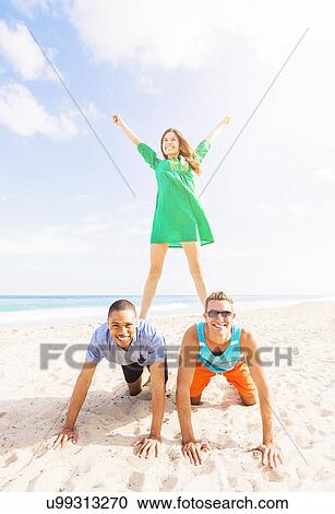 Young people making human pyramid on beach View Large Photo Image Stock Image - Young people making human pyramid on beach. Fotosearch