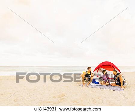 Stock Image - Young people relaxing on beach. Fotosearch