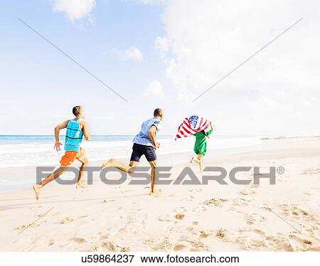 Stock Photo - Young people running with American flag on beach. Fotosearch
