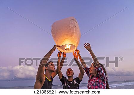 Young people with illuminated lantern on beach View Large Photo Image Stock Image - Young people with illuminated lantern on beach. Fotosearch