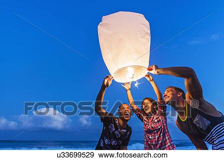 Young people with illuminated lantern on beach View Large Photo Image Stock Photo - Young people with illuminated lantern on beach. Fotosearch