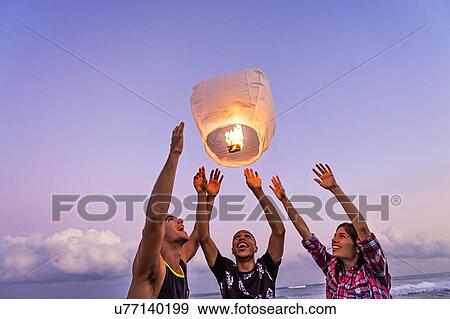 Young people with illuminated lantern on beach View Large Photo Image Stock Photo - Young people with illuminated lantern on beach. Fotosearch